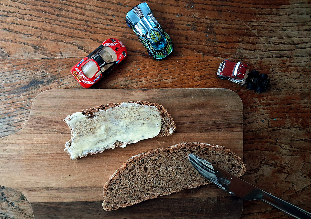 Was ist Familienkultur. Ein Frühstücksbrett mit zwei Broten, daneben stehen Spielzeugautos.